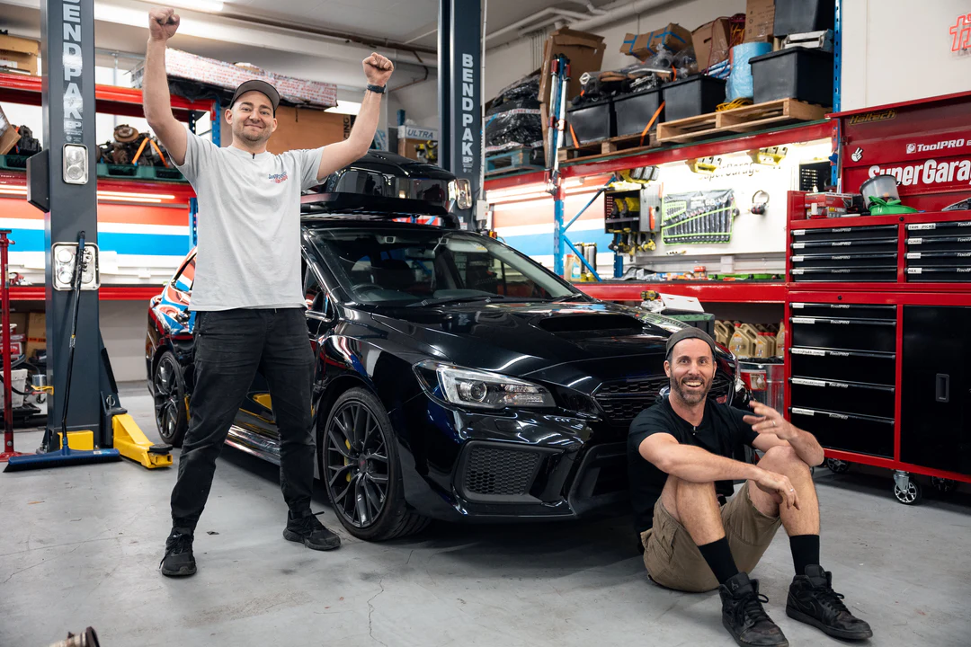 Mighty Car Mods team celebrating partnership with Xtreme Clutch in professional workshop with performance clutch installation and branding display