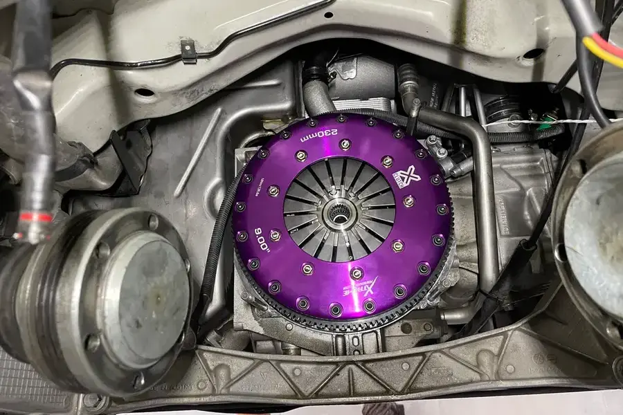 Porsche 996/997 Cup car with triple-plate ceramic clutch upgrade installed, showing high-performance clutch components in professional workshop setting